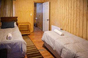 科克拉内Hostal Lejana Patagonia的木墙客房的两张床