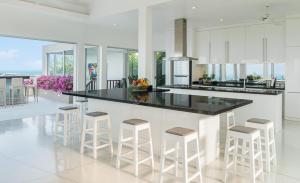 曾蒙海滩Baan Bon Khao - Seaview Private Villa的厨房配有白色橱柜、黑色柜台和凳子