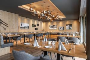 加舒恩Sporthotel Chalet的餐厅设有木桌、椅子和吊灯。