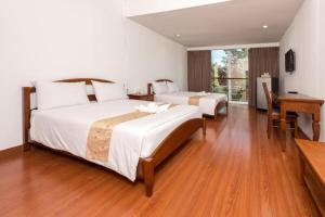 乌汶班萱坤塔高尔夫度假酒店的一间卧室设有两张床、一张桌子和一个窗口。