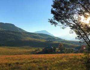 萨尼山口Sani Lodge Self-Catering Cottages Sani Pass South Africa的享有山脉背景的田野景色