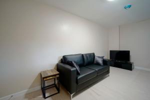 哈德斯菲尔德Alpha Lofts, Huddersfield的客厅设有一张黑色皮沙发,配有电视