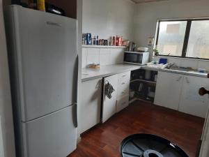 帕帕莫阿Papamoa Holiday Home的厨房铺有木地板,配有白色冰箱。