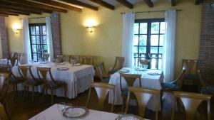 杜鲁埃洛德拉谢拉卡萨罗慕洛酒店的餐厅设有白色的桌椅和窗户。