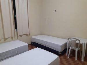 福塔莱萨Hostel Parquelândia的一间设有两张床和椅子的房间