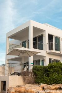 普罗维登西亚莱斯岛SulMare at Sapodilla Bay Luxury villas的带阳台和遮阳伞的白色房屋