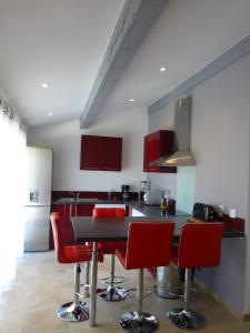 萨尔里昂红磨坊度假屋的厨房配有红色椅子和黑色台面