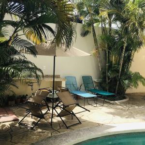 坎昆皮凯里住宿加早餐旅馆的一组椅子和一把遮阳伞,位于游泳池旁
