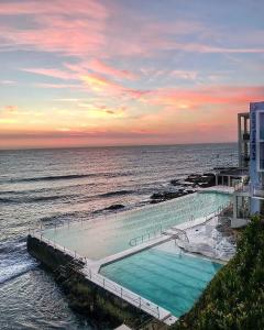 悉尼Premium Bondi Beach 2 Bedroom with Beach view and parking的日落时分在海边的游泳池