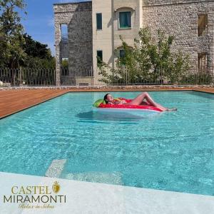 塞尔瓦迪法萨诺Hotel Castel Miramonti的躺在游泳池里的木筏上的男人