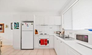 Safety BayIsland Villas Accommodation Unit 4-108 Arcadia Drive Shoalwater的厨房配有白色橱柜和白色冰箱。