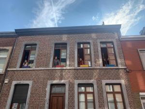 列日Espace Douffet - Un havre de paix en pleine ville的一群人看着砖砌建筑的窗户