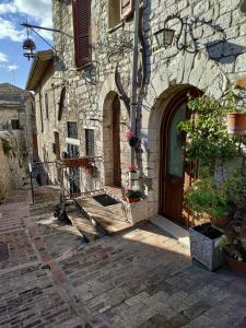 阿西西Le Casette di Franco & Anna的一座古老的石头建筑,设有木门和鲜花