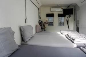 春武里帕投伊之家旅馆的房间里的一排白色的床