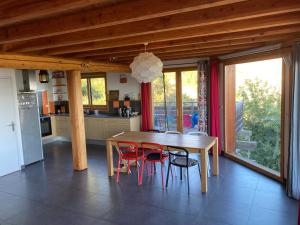 Saint-ApollinaireChalet bioclimatique avec vue sur le lac de Serre Ponçon的厨房配有木桌和红色椅子
