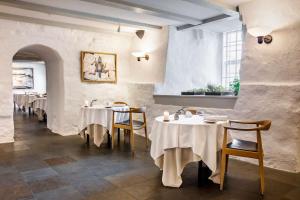 Hørve得索姆酒店的餐厅设有白色的桌椅和窗户。