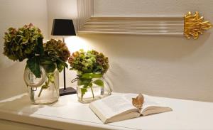 圣玛格丽塔-利古雷圣安德烈亚酒店的一张桌子,上面有两瓶花,一本书和鲜花