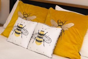 TurriffNetherdale House & The Coach House的床上的四个枕头,上面涂有蜜蜂