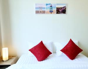素叻บ้านคุณพระ แอท โกเตง的卧室配有带红色枕头的白色床