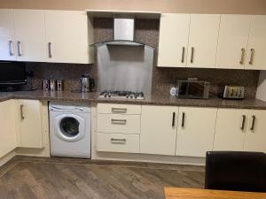 Troed-y-rhiwS&Ks的厨房配有白色橱柜和洗衣机。