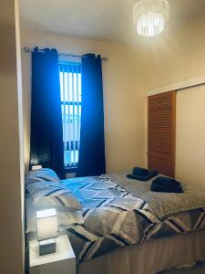 拉格斯Largs Holiday Apartment的一间卧室配有一张带蓝色窗帘的床和一扇窗户
