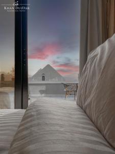 开罗Khan Duidar Inn - Pyramids View Rooftop的卧室配有一张床,享有金字塔的景色