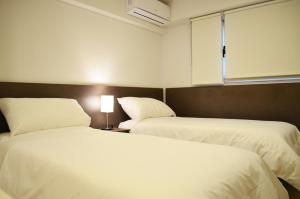 罗卡将军市Hotel Bait的配有白色床单的酒店客房内的两张床