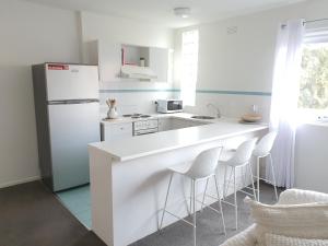 墨尔本Royal Park Retreat的白色的厨房配有白色冰箱和凳子