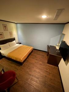 台东假期商务旅馆的一间卧室配有一张床、一把椅子和一张桌子