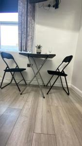 哈德斯菲尔德bvapartments-Queensgate 2的一张桌子和两把椅子,位于一间铺有木地板的房间里