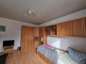 韦斯特兰Mein Urlaub auf Sylt的一间卧室配有一张床、一台电视和木制橱柜。