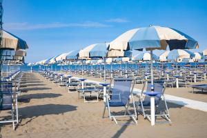 格罗塞托港地中海公寓酒店的海滩上的一排椅子和遮阳伞