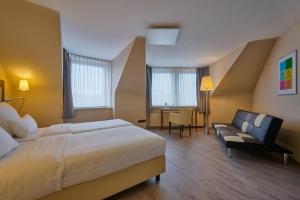 亚琛Cityhotel Kaiser Karl Aachen的酒店客房配有一张床、一把椅子和一张书桌