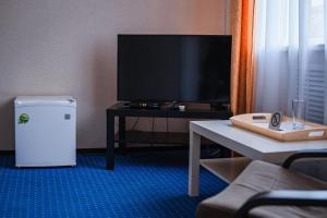 AksayComfort Hotel的客厅配有电视和带桌子的桌子。