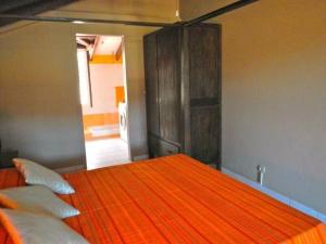 德赛duplex, 2 bedrooms, 2 couples sea view overlooking the village of DESHAIES的一间卧室配有带橙色床单和枕头的床。