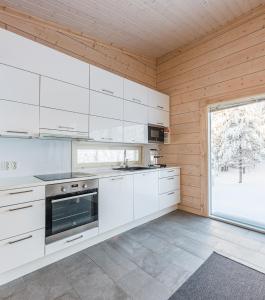 鲁卡Rokovan Helmi - Natural peace in Ruka-Kuusamo的一间厨房,配有白色的橱柜和大窗户