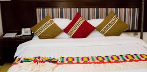 阿克拉Sonia Hotel的一张白色的床,上面有色彩缤纷的枕头