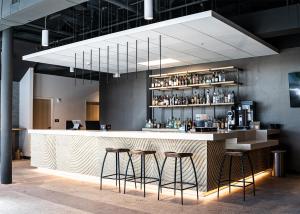达拉斯SOVA Micro-Room & Social Hotel的酒吧设有2张凳子和1个带饮品的吧台