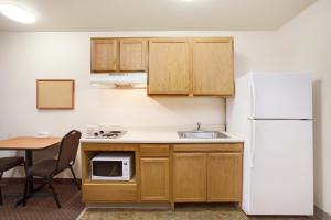 奥德萨WoodSpring Suites Odessa的厨房配有桌子和白色冰箱。