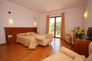蒙特普齐亚诺Hotel Panoramic Montepulciano的一间卧室配有一张床、一张沙发和一个窗口