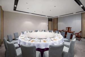 东莞东莞东城华美达安可酒店的一间会议室,配有大桌子和椅子