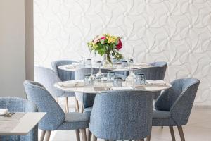 普拉加德阿罗Hotel Planamar by Escampa Hotels的一张桌子,上面摆放着蓝色的椅子和花瓶
