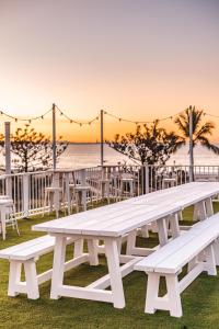 黄金海岸The Pink Hotel Coolangatta的一张白色野餐桌,俯瞰着日落时的海滩