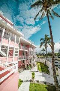 黄金海岸The Pink Hotel Coolangatta的前面有棕榈树的粉红色建筑