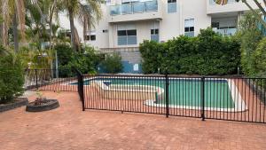 黄金海岸Homely Inn Hostel的大楼前带游泳池的黑色围栏