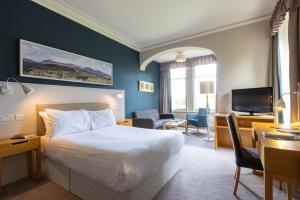 斯特拉斯佩弗The Highland Hotel by Compass Hospitality的酒店客房配有一张床、一张书桌和一台电视。