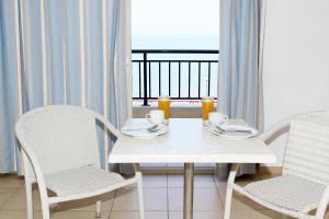 新马尔马拉斯米拉马雷公寓式酒店的一张带两把椅子的白色桌子和一张带杯子的桌子