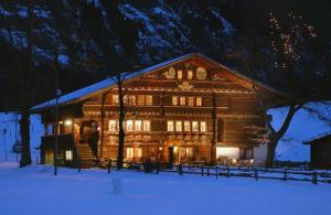 坎德施泰格蓝加索夫卢迪豪斯酒店的一座大木屋,晚上在雪中