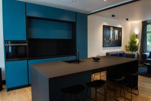 斯特拉斯堡JAMES Résidence & Spa的一间设有蓝色橱柜的厨房和一间带凳子的酒吧