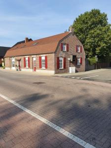 NeerpeltB&B Le Jardin的街上有红百叶窗的砖砌建筑
